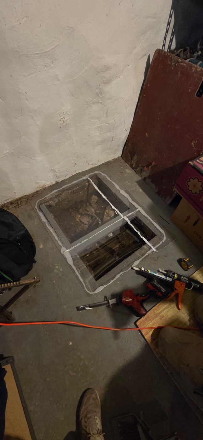 A sub-slab suction pit cut and sealed into a basement floor for radon mitigation